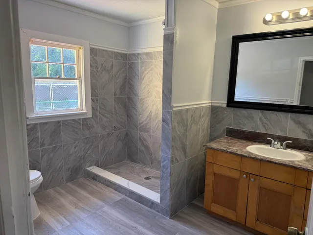 a bathroom with a granite countertop sink a mirror and shower