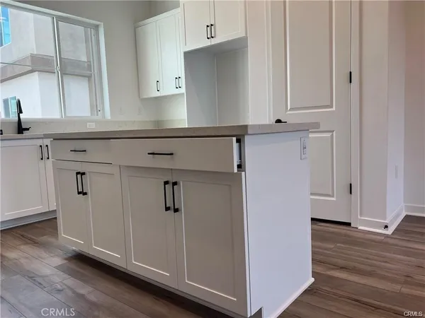 a kitchen with white cabinets and wooden floor