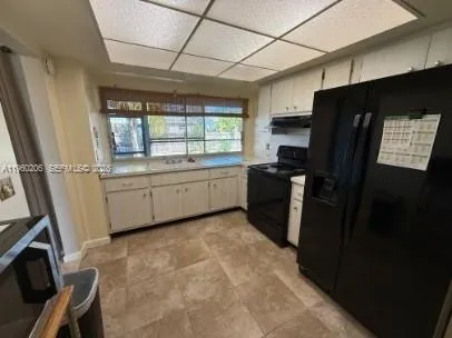 a kitchen with a sink a refrigerator a window and cabinets