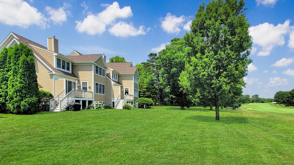 a view of a white house with a big yard and potted plants and large trees