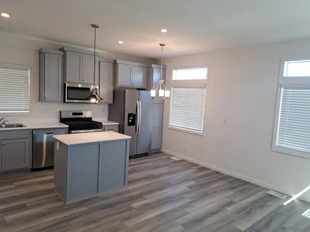 a kitchen with a refrigerator a stove top oven a sink and dishwasher with wooden floor