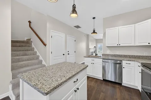 a kitchen with white cabinets and chandelier