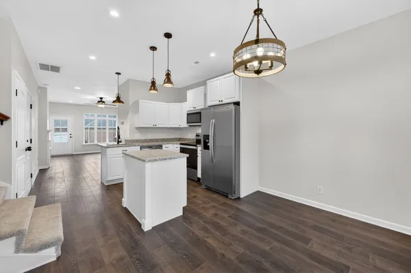 a large kitchen with stainless steel appliances granite countertop a hardwood floor and a chandelier