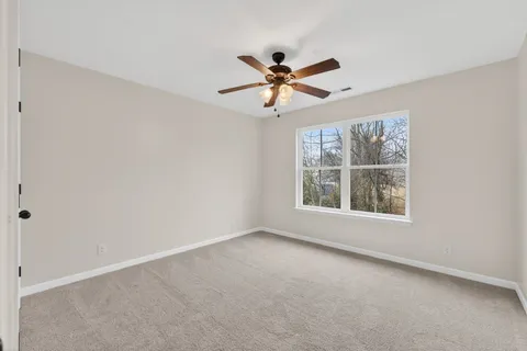 an empty room with a window and a fan