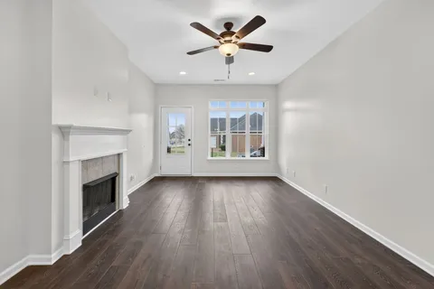 an empty room with wooden floor fireplace and windows