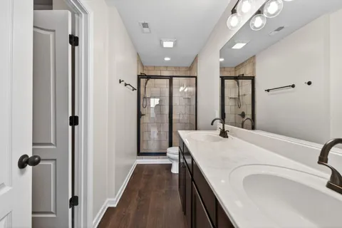 a en suite bathroom with a granite countertop sink a toilet a mirror and shower