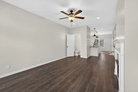 a view of an empty room with wooden floor and a ceiling fan