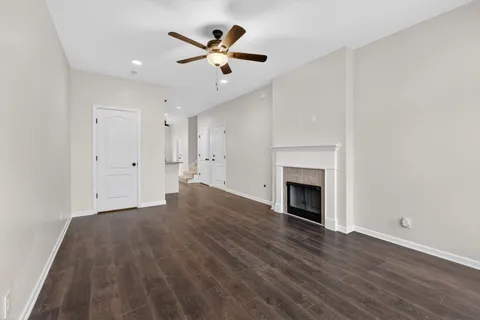 a view of an empty room with wooden floor and a fireplace