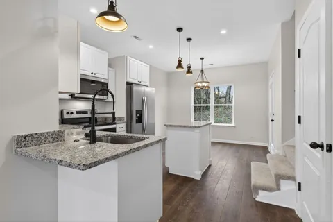 a kitchen with stainless steel appliances granite countertop a sink a refrigerator and a wooden floor