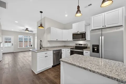 a kitchen with granite countertop a stove a sink and a refrigerator