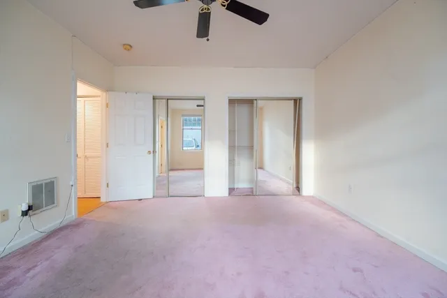 an empty room with windows and fan