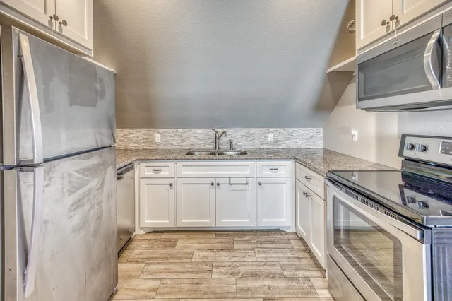 a kitchen with granite countertop a sink stove and cabinets