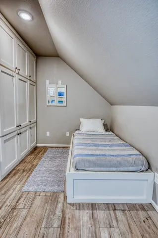 a spacious bedroom with a bed and wooden floor