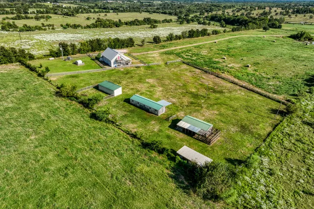 an aerial view of residential houses with outdoor space and trees