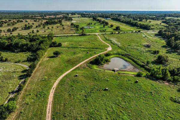an aerial view of a residential houses with outdoor space and trees
