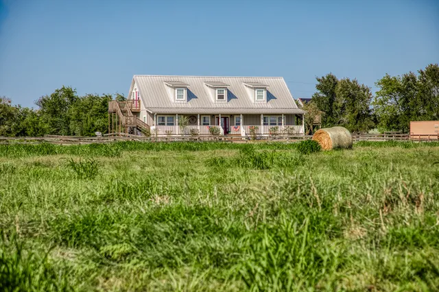 a view of a house with a big yard and large trees