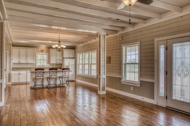 a view of a big room with wooden floor and a kitchen