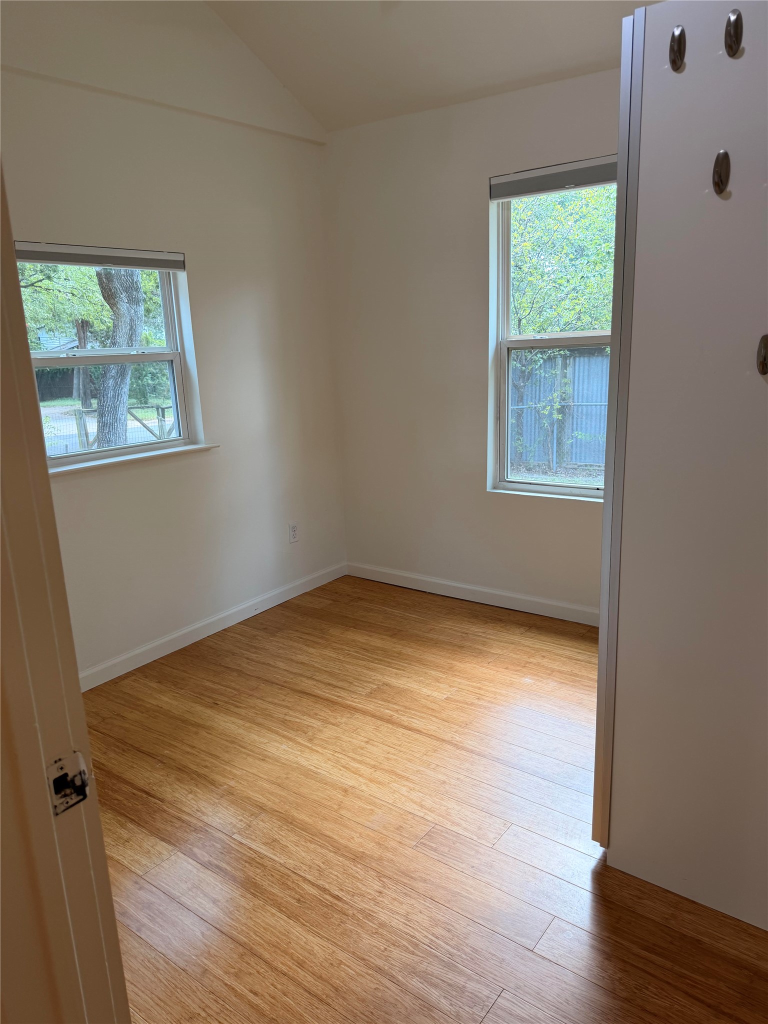1182 Pandora Street Austin, TX 78702 - Photo 5 of 19 Natural light filters through two windows, illuminating the durable hardwood flooring in this cozy bedroom space.