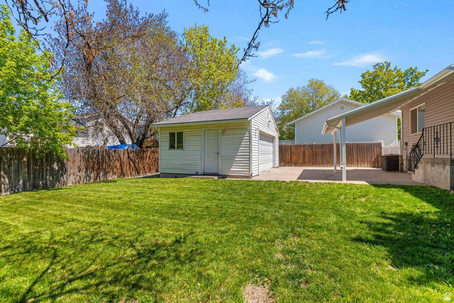 415 East 1150th Street North Logan, UT 84341 - Photo 31 of 38 Expansive fenced backyard featuring a detached garage, a concrete patio, and a covered patio area