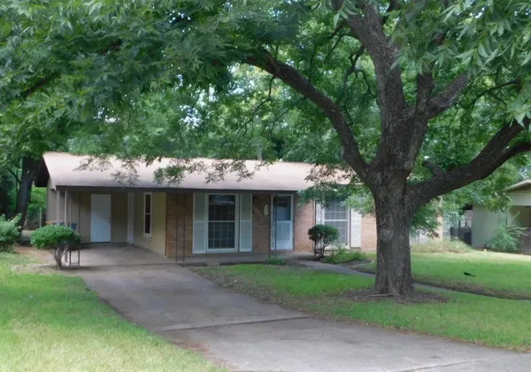 a view of a house with a yard and large tree