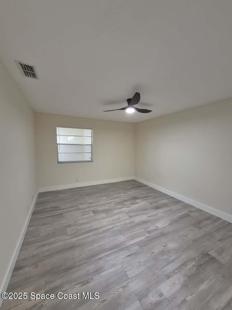 1341 Cheney Highway, Unit H Titusville, FL 32780 - Photo 12 of 16 an empty room with wooden floor and windows