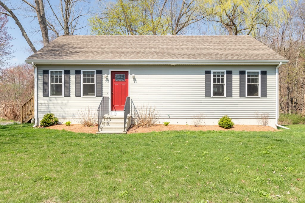 a front view of a house with a yard and a tree