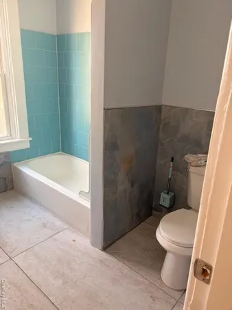 a white toilet sitting next to a bath tub