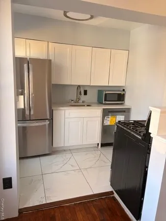 a kitchen with granite countertop a refrigerator and a stove top oven