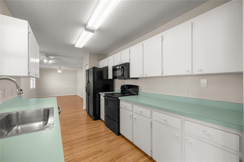 8478 Southwest 61st Terrace Road Ocala, FL 34476 - Photo 16 of 39 a kitchen with stainless steel appliances granite countertop a sink a stove top oven a refrigerator with white cabinets and couches