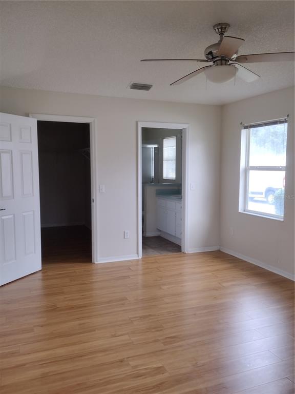 8478 Southwest 61st Terrace Road Ocala, FL 34476 - Photo 22 of 39 an empty room with wooden floor chandelier fan and windows