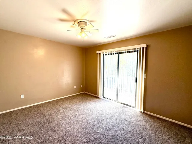 an empty room with a fan & a window