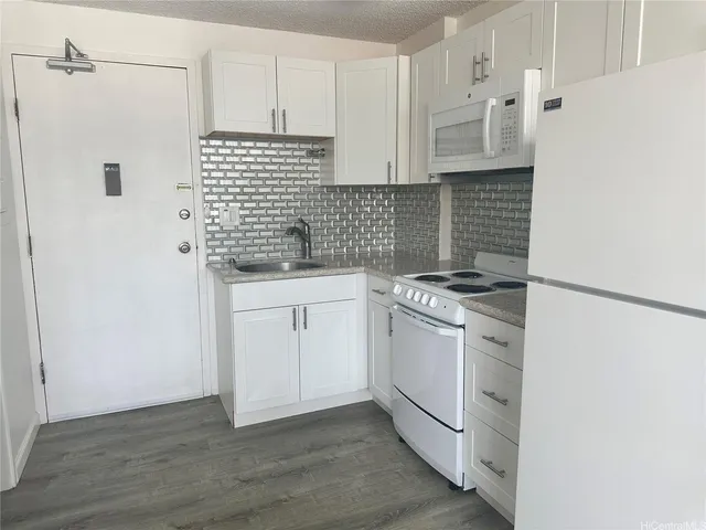 a kitchen with granite countertop white cabinets and white appliances