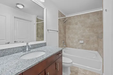 a bathroom with a granite countertop sink a toilet and shower