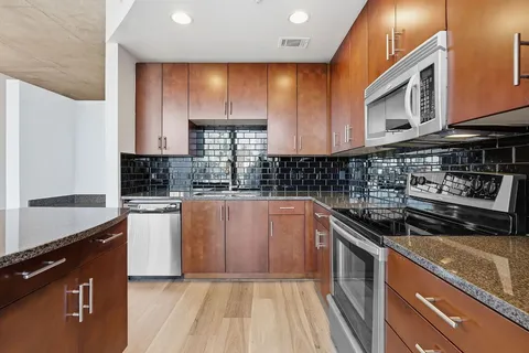 a kitchen with stainless steel appliances granite countertop a sink a stove a microwave cabinets and a counter top space