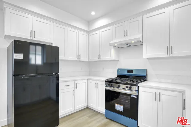 a kitchen with stainless steel appliances white cabinets and a stove a refrigerator with wooden floor