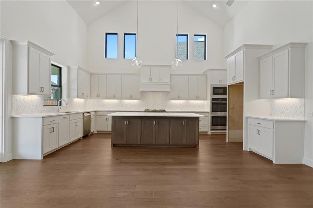 4626 Rillstone Road Midlothian, TX 76065 - Photo 9 of 40 Kitchen featuring high vaulted ceiling, white cabinetry, decorative backsplash, a center island, and pendant lighting