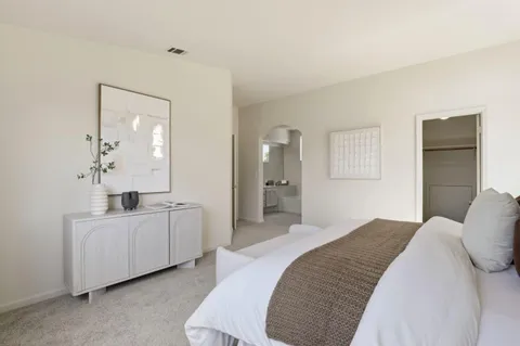 a bedroom with a bed a mirror and a dresser