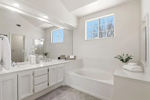 a bathroom with a tub a sink and mirror