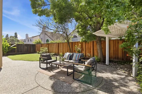 a view of a patio with table and chairs potted plants and a large tree
