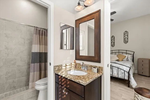 a bathroom with a granite countertop sink a toilet and a shower