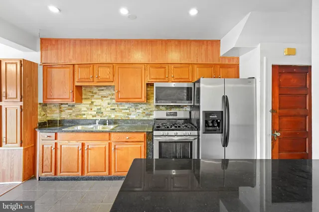a kitchen with stainless steel appliances granite countertop a refrigerator a stove and a sink