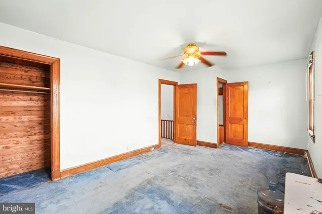 an empty room with closet and a chandelier fan