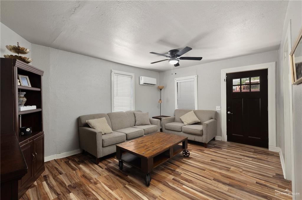 411 East 4th Street Rio Grande City, TX 78582 - Photo 2 of 12 Living area featuring wood-finish flooring, a dark paneled entry door with frosted glass, and white window blinds