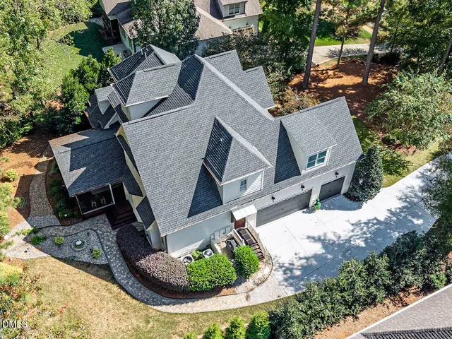 an aerial view of a house with a yard and a large tree