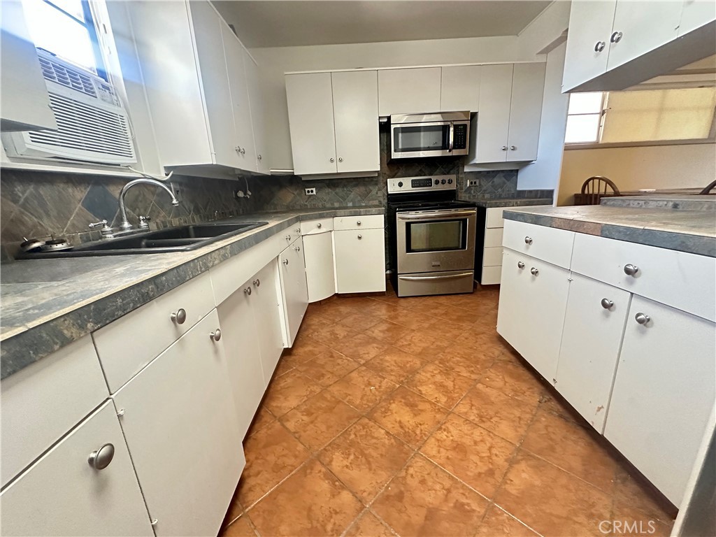 1602 Collins Street Needles, CA 92363 - Photo 5 of 18 a kitchen with granite countertop a sink a stove top oven and cabinets