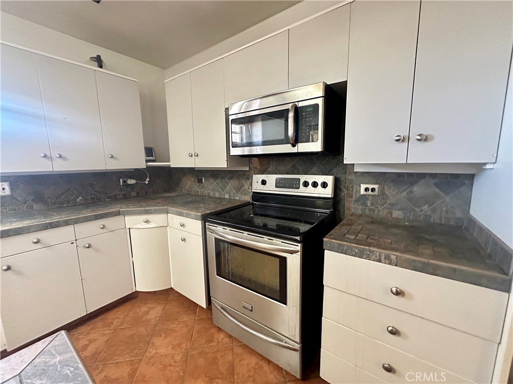 1602 Collins Street Needles, CA 92363 - Photo 6 of 18 a kitchen with stainless steel appliances granite countertop white cabinets stove and microwave