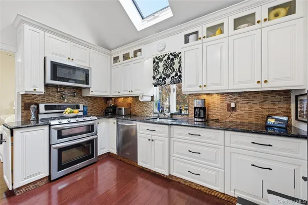 a kitchen with granite countertop white cabinets and stainless steel appliances