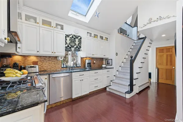 a kitchen with granite countertop a sink cabinets stainless steel appliances and wooden floor