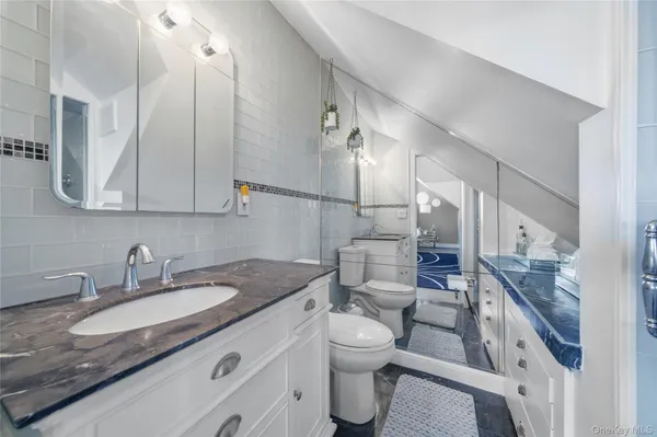 a bathroom with a granite countertop sink a toilet a mirror and shower