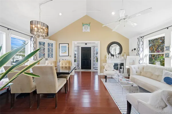 a living room with couches a dining table with wooden floor and a chandelier